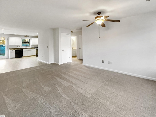 unfurnished living room with sink, ceiling fan, and light colored carpet