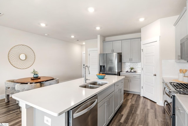 kitchen featuring sink, decorative backsplash, dark hardwood / wood-style flooring, a kitchen island with sink, and appliances with stainless steel finishes