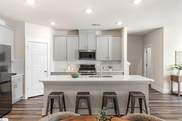 kitchen featuring sink, a kitchen bar, an island with sink, and appliances with stainless steel finishes