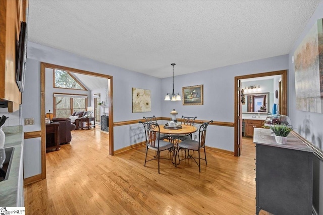 dining area featuring a textured ceiling, light hardwood / wood-style floors, and a notable chandelier