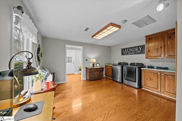 kitchen with a textured ceiling, light wood-type flooring, washing machine and dryer, and sink