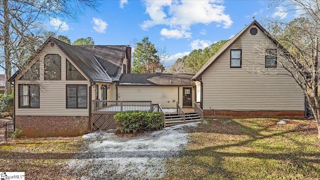 rear view of house featuring a wooden deck and a lawn