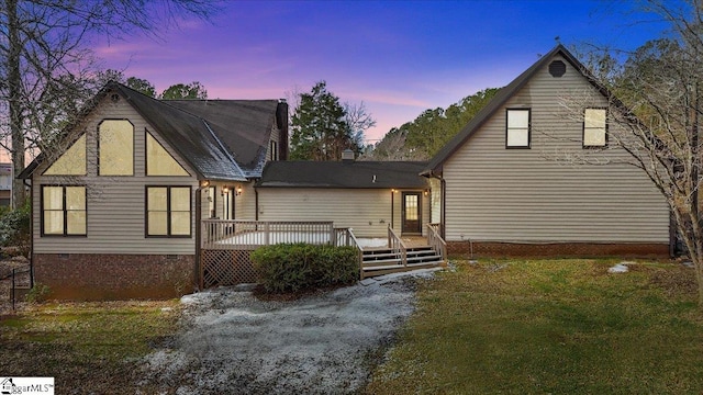 back house at dusk with a lawn and a deck