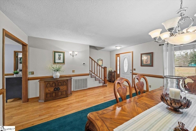 dining space with hardwood / wood-style flooring, a textured ceiling, and a chandelier