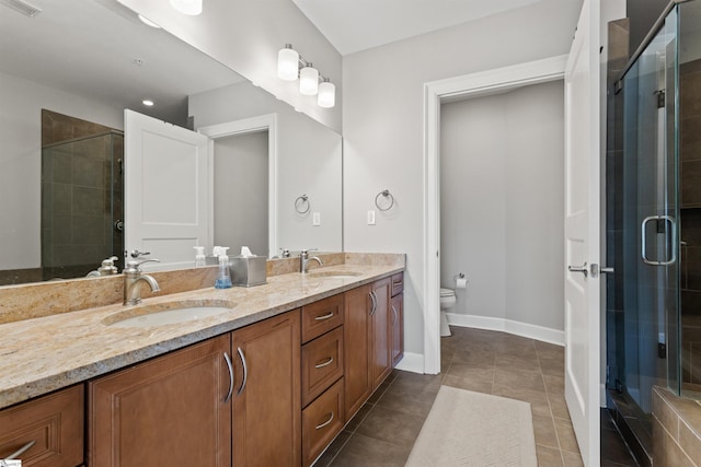 bathroom featuring toilet, a shower with door, vanity, and tile patterned floors