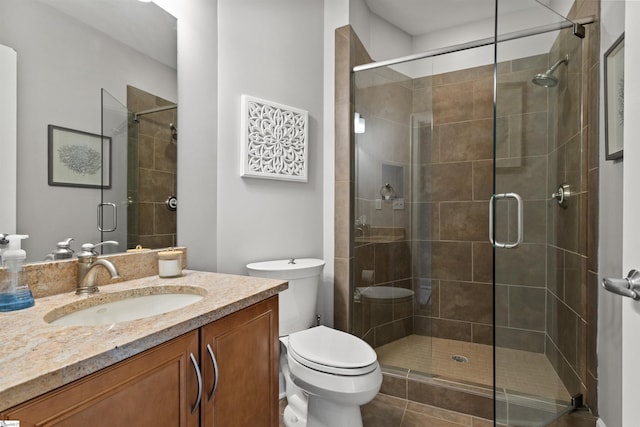 bathroom with toilet, a shower with door, and vanity