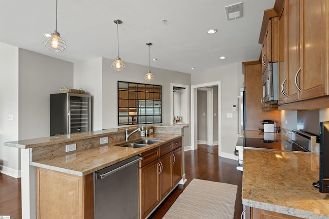 kitchen with decorative light fixtures, stainless steel appliances, a kitchen island with sink, and sink