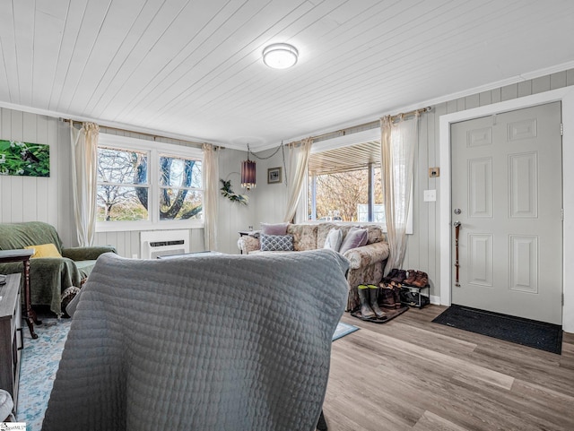 interior space with wood ceiling, ornamental molding, a wall mounted air conditioner, and light hardwood / wood-style floors