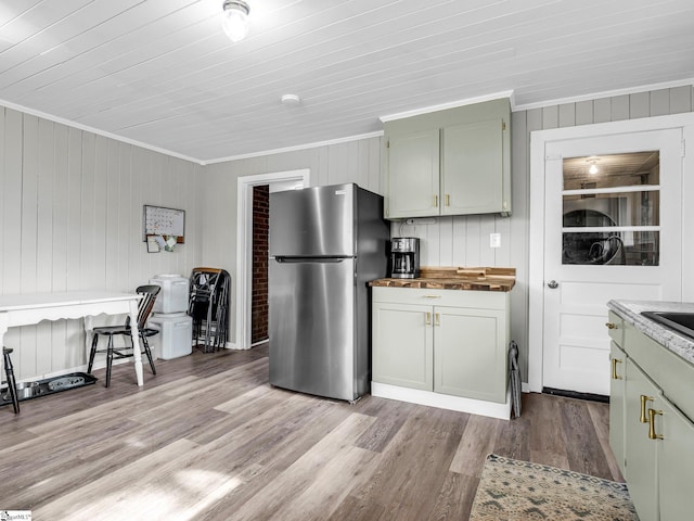 kitchen featuring wooden ceiling, wood walls, crown molding, stainless steel fridge, and light hardwood / wood-style flooring