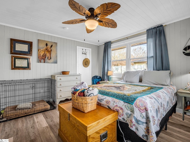 bedroom with ornamental molding, wood walls, ceiling fan, and wood-type flooring