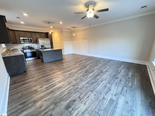 kitchen with appliances with stainless steel finishes, decorative light fixtures, sink, a center island, and crown molding