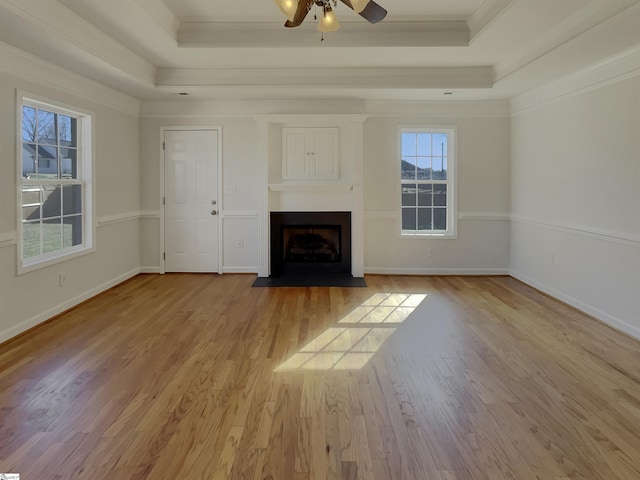 unfurnished living room with ornamental molding, ceiling fan, light hardwood / wood-style flooring, and a tray ceiling