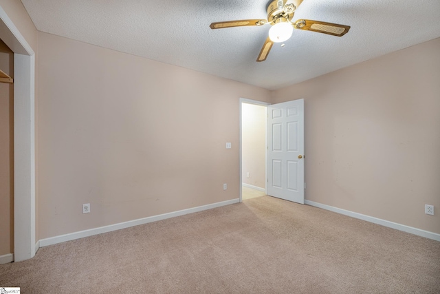 unfurnished bedroom with ceiling fan, light colored carpet, and a textured ceiling