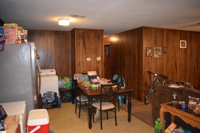 dining space with washer / clothes dryer, wood walls, and a textured ceiling