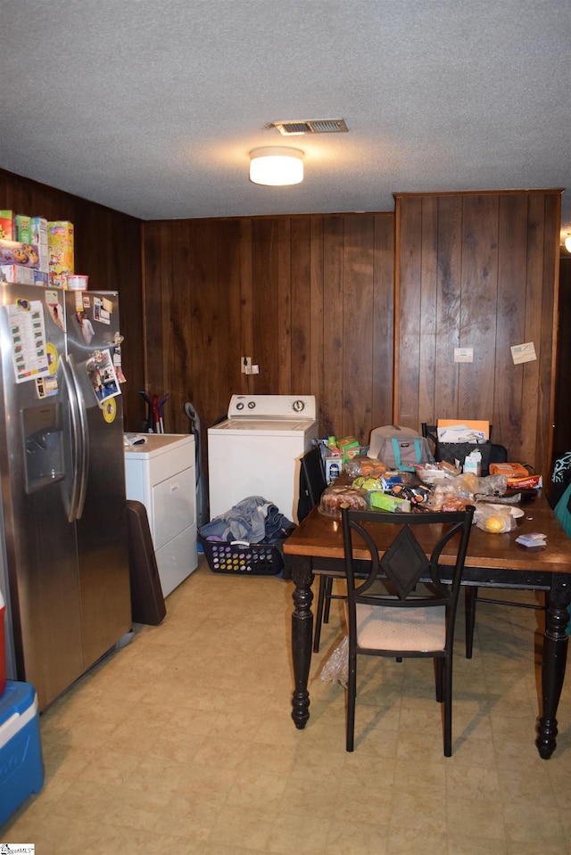 dining area with wooden walls, washing machine and clothes dryer, and a textured ceiling