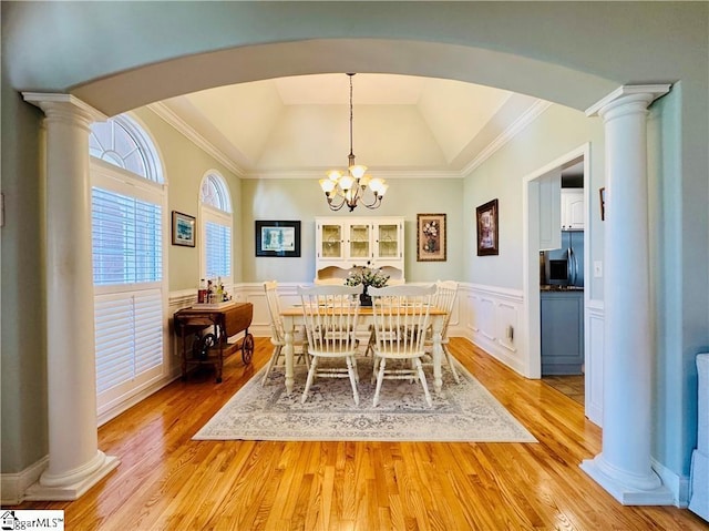 dining room featuring ornamental molding, light wood-type flooring, an inviting chandelier, and a tray ceiling