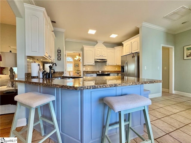 kitchen with kitchen peninsula, appliances with stainless steel finishes, white cabinetry, and a kitchen bar