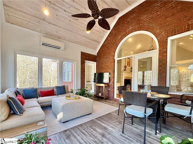 living room with a wall mounted AC, wooden ceiling, high vaulted ceiling, and brick wall