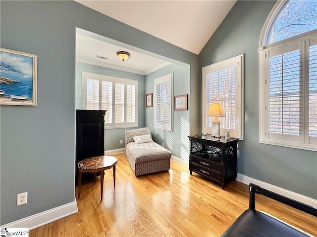 living area featuring a wealth of natural light, crown molding, light wood-type flooring, and lofted ceiling