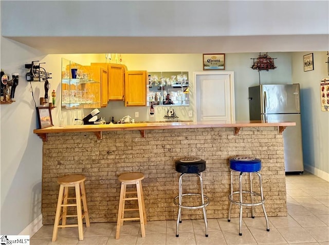 bar with stainless steel fridge and light tile patterned floors