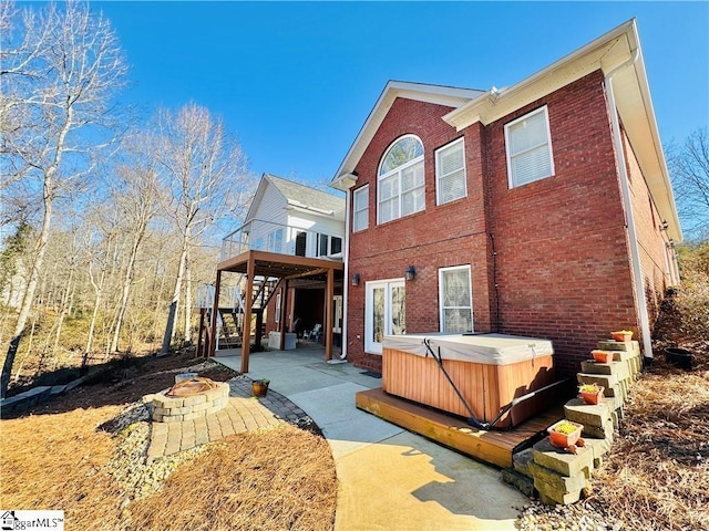 rear view of house featuring an outdoor fire pit, a deck, a hot tub, and a patio