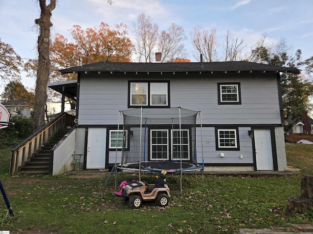 back of house featuring a yard and a trampoline