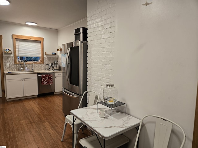 kitchen featuring light stone counters, backsplash, white cabinetry, appliances with stainless steel finishes, and sink