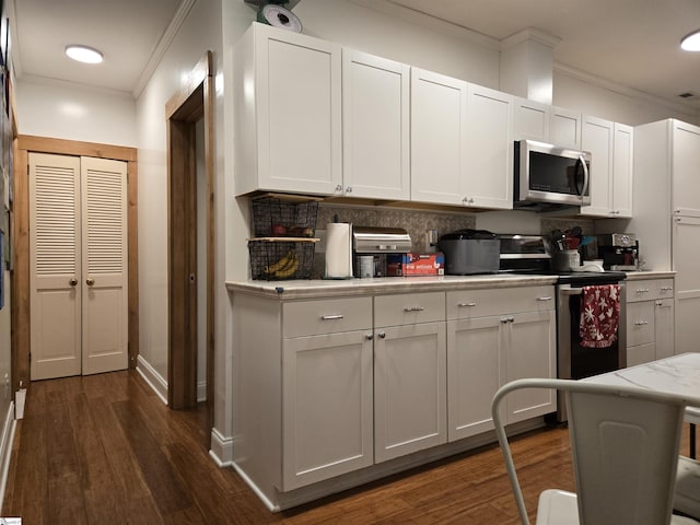 kitchen with white cabinets, ornamental molding, decorative backsplash, dark hardwood / wood-style flooring, and appliances with stainless steel finishes