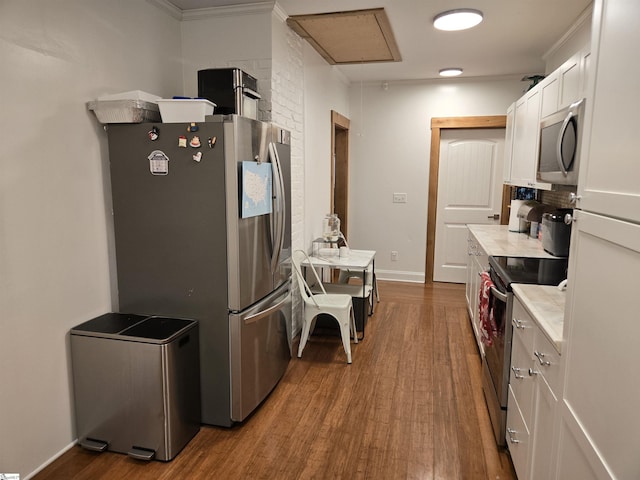 kitchen with stainless steel appliances, ornamental molding, dark hardwood / wood-style flooring, and white cabinetry