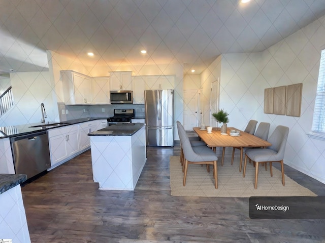 kitchen featuring a center island, white cabinetry, dark stone counters, appliances with stainless steel finishes, and sink