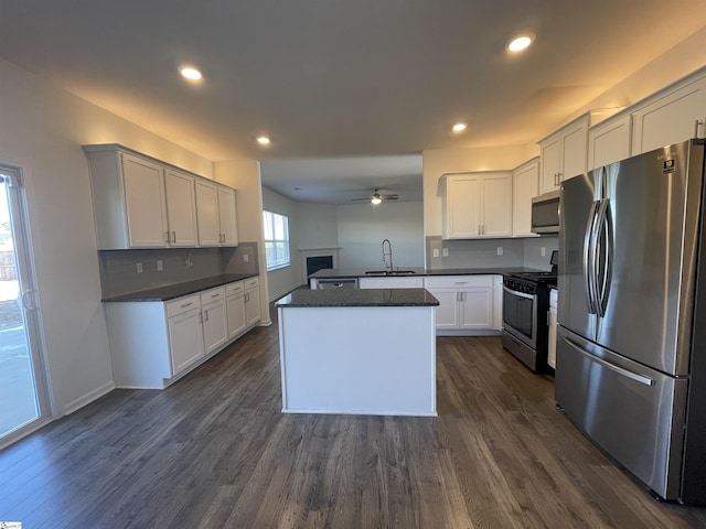 kitchen with appliances with stainless steel finishes, dark wood-type flooring, white cabinets, and kitchen peninsula