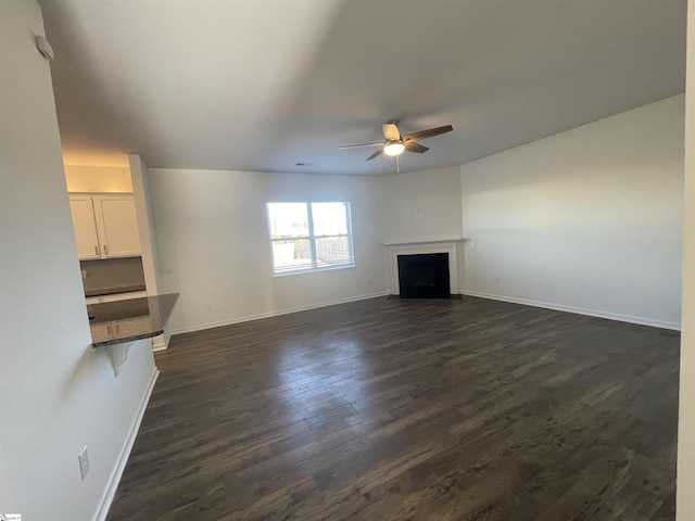 unfurnished living room featuring ceiling fan and dark hardwood / wood-style flooring