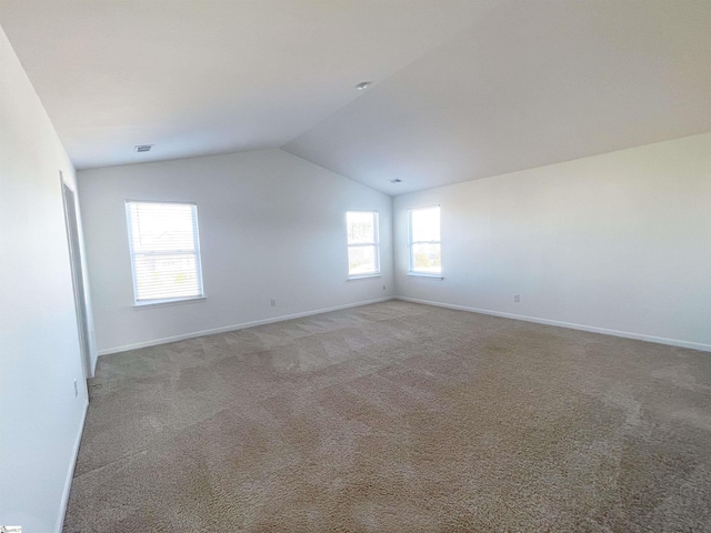 carpeted empty room with vaulted ceiling