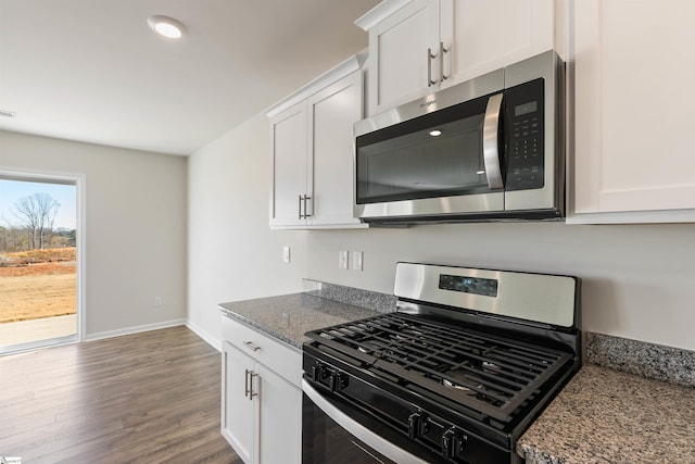 kitchen featuring stainless steel appliances, white cabinets, dark stone countertops, and hardwood / wood-style flooring