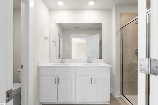 bathroom with vanity, a shower with shower door, and toilet