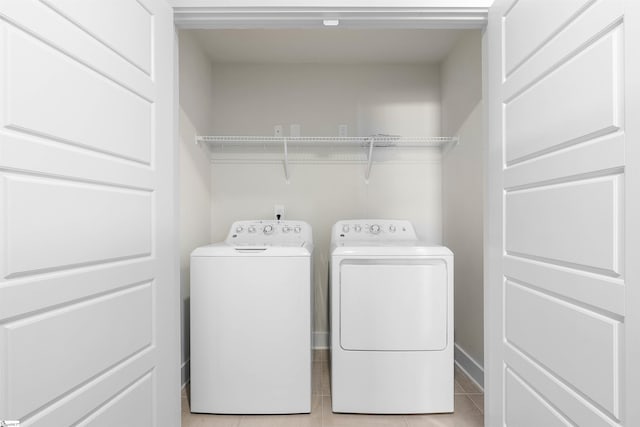 laundry area with washing machine and dryer and light tile patterned floors