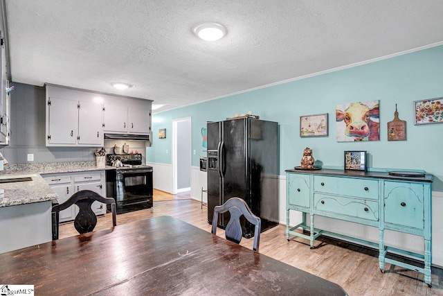 kitchen with black appliances, light hardwood / wood-style floors, sink, and a textured ceiling