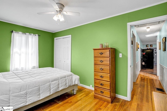 bedroom featuring ornamental molding, ceiling fan, light hardwood / wood-style flooring, and a closet