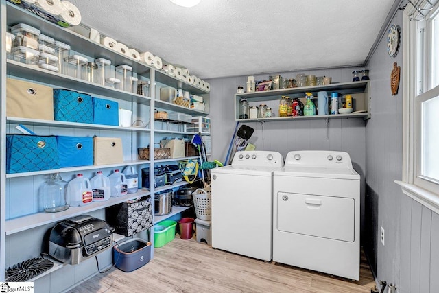 laundry room with a textured ceiling, light hardwood / wood-style floors, and separate washer and dryer