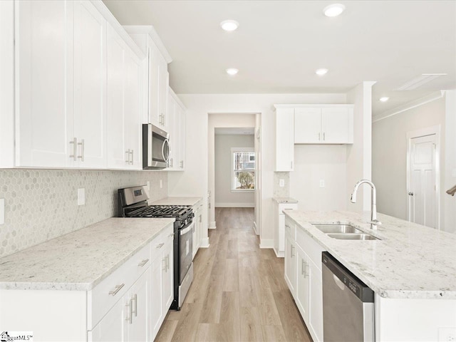 kitchen with appliances with stainless steel finishes, white cabinetry, light wood-type flooring, and sink