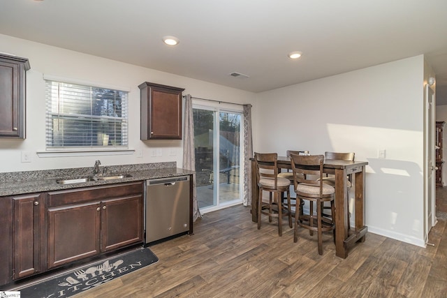 kitchen featuring dark hardwood / wood-style flooring, dark stone countertops, dishwasher, and dark brown cabinetry