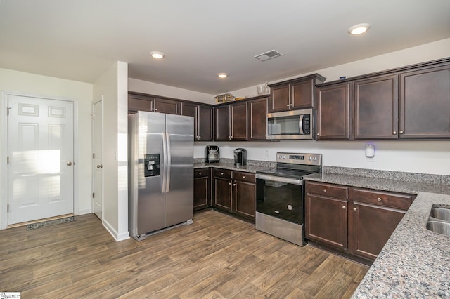 kitchen featuring light stone countertops, dark wood-type flooring, dark brown cabinets, and appliances with stainless steel finishes