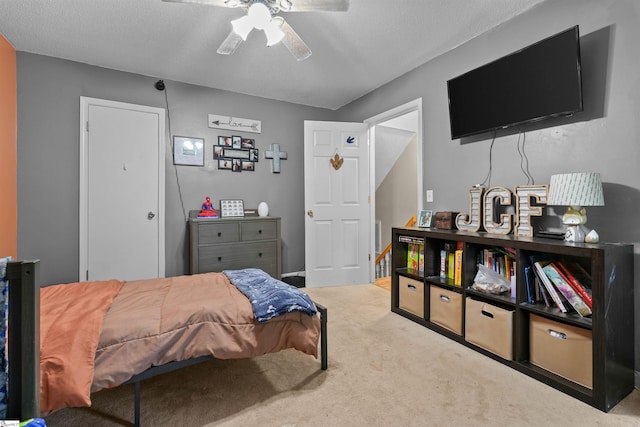 carpeted bedroom featuring a textured ceiling and ceiling fan