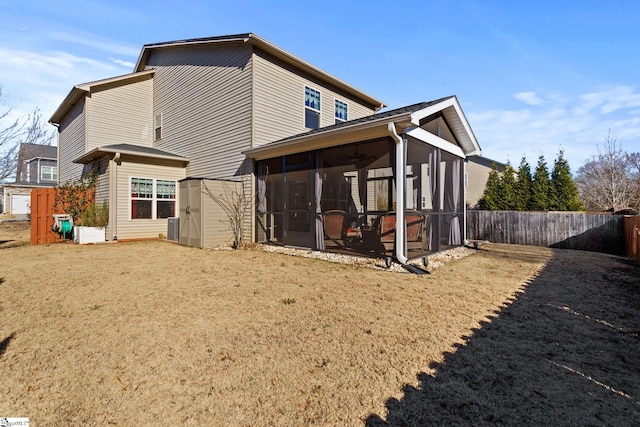 rear view of house with a lawn, central AC unit, and a sunroom