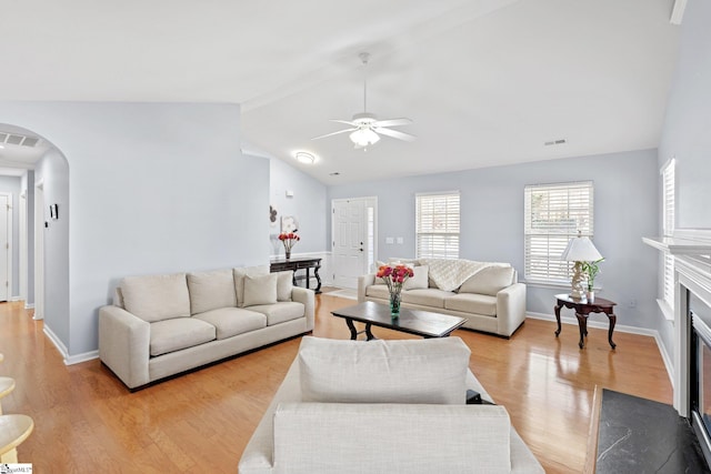 living room with lofted ceiling, a fireplace, light wood-type flooring, and ceiling fan