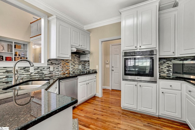 kitchen with stainless steel appliances, sink, white cabinets, dark stone countertops, and ornamental molding