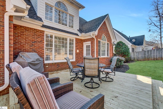 wooden terrace featuring a grill and a lawn