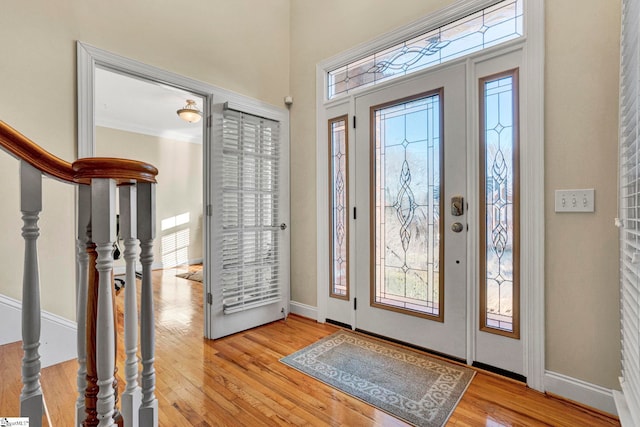 entryway with ornamental molding and light hardwood / wood-style flooring