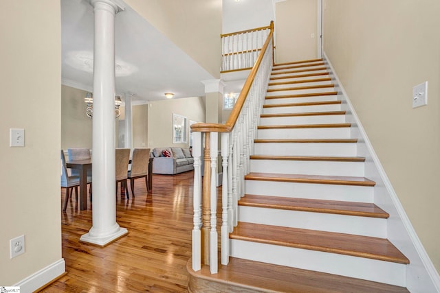 staircase with ornamental molding, hardwood / wood-style floors, and decorative columns