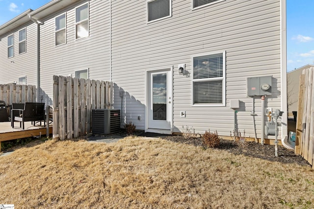 back of house with central AC unit, a deck, and a lawn